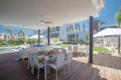 an outdoor dining area with white chairs and tables at Villa Olivine Pearl 3 in Protaras