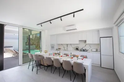 a white kitchen and dining room with a table and chairs at Kube Luxury Villas in Ayia Napa
