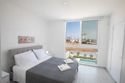 a bedroom with a bed and a large window at Walk to Protaras Center & Beach- Your Dream Escape, Blue Island Villa in Protaras