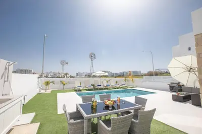 a patio with a table and chairs and a swimming pool at Walk to Protaras Center & Beach- Your Dream Escape, Blue Island Villa in Protaras