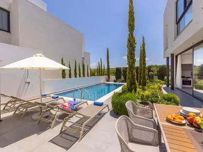 a patio with a table and chairs and a swimming pool at Almaria Residences in Paralimni