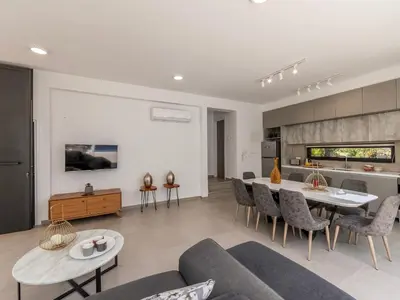 a living room with a table and chairs and a kitchen at Almaria Residences in Paralimni