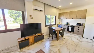 a kitchen with a table and a large screen tv at Mimi's Sunny Beach Apartment in Larnaka