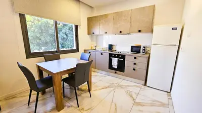 a kitchen with a table and a refrigerator at Mimi's Sunny Beach Apartment in Larnaka