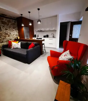 a living room with a red couch and a kitchen at BELLE VUE Mountain Home in Kalopanayiotis