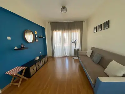 a living room with a couch and a blue wall at Aphrodite Sea View Apartment in Larnaka