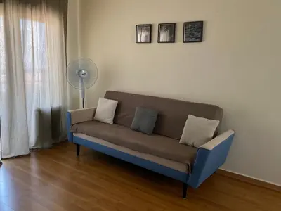 a couch sitting in a living room next to a window at Aphrodite Sea View Apartment in Larnaka