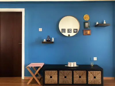 a room with a blue wall with a mirror and a table at Aphrodite Sea View Apartment in Larnaka