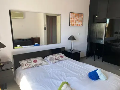 a bedroom with a white bed with a large mirror at private room in a shared flat at best location in Limassol