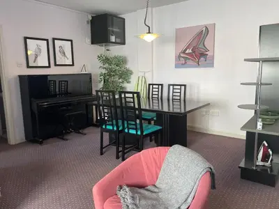 a living room with a table and chairs and a piano at private room in a shared flat at best location in Limassol