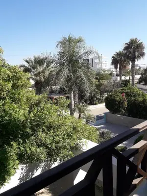 a view of a balcony with palm trees and a building at SEAFRONT BEACH PARTY VILLA in Pervolia