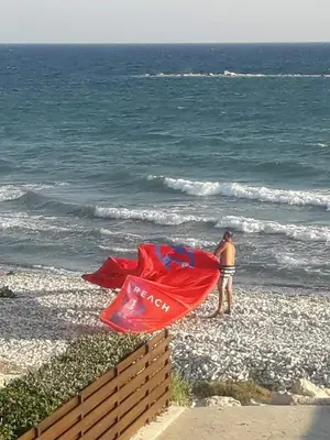 a man standing on the beach with a red kite at SEAFRONT BEACH PARTY VILLA in Pervolia