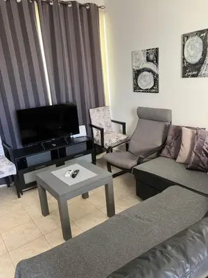 a living room with couches and a tv and a table at Protaras, Janas apartment in Protaras