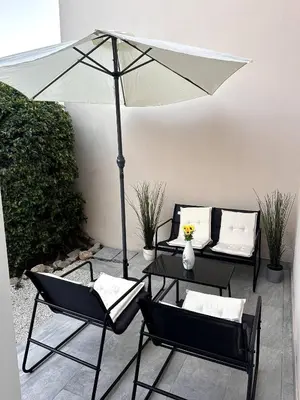 a patio with two chairs and an umbrella at Olymbos Garden Apartment IV in Ayia Napa