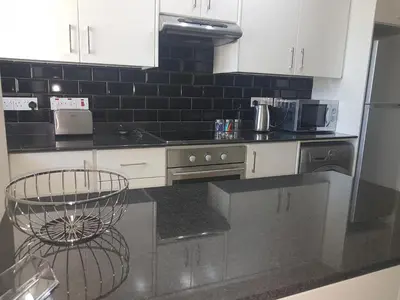 a kitchen with white cabinets and a black counter top at Panorama Village Complex in Paralimni