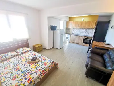a bedroom with a bed and a couch and a kitchen at Hidden Gem City Studio in Larnaka