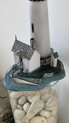 a model of a lighthouse on a glass table with shells at Trident Beach Apartment in Protaras