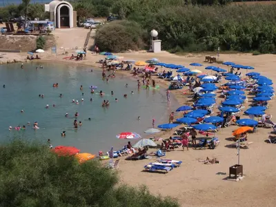 a group of people on a beach with umbrellas at Trident Beach Apartment in Protaras