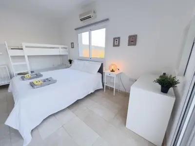 a white bedroom with two beds and a window at Grand villa Lynn seaview Ayia Napa in Ayia Napa