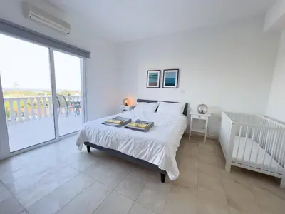 a white bedroom with a bed and a large window at Grand villa Lynn seaview Ayia Napa in Ayia Napa