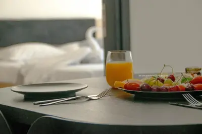a table with a plate of fruit and a glass of orange juice at Mad beach in Protaras