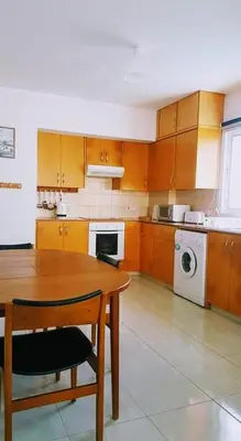 a kitchen with a table and a washing machine at Armstrong Apartment in Paralimni