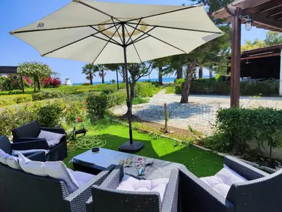 a patio with a table and an umbrella at Pampering Beach Dream, A Stunning Luxury Retreat at Yialos Village in Meneou