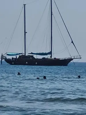a sail boat in the ocean with people swimming in the water at Alex Beach Apartment 34 in Larnaka