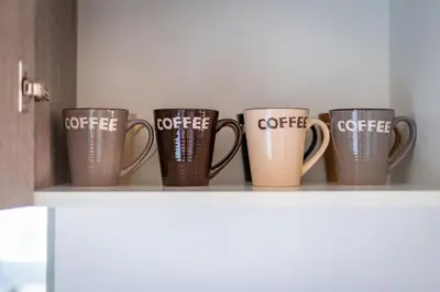 a row of coffee cups sitting on a shelf at Majestic Sunset Salt Lake Views 300m from beach in Larnaka