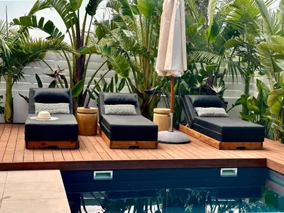 a patio with two beds and an umbrella next to a pool at Lora Pearl Luxury Villa in Protaras