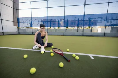 a young man sitting on a tennis court with tennis balls at The Icon Limassol in Limassol