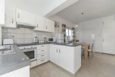 a white kitchen with white cabinets and a table at Lemon Tree Villa in Paralimni