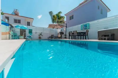 a swimming pool with blue water in front of a building at Lemon Tree Villa in Paralimni