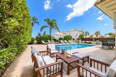 a patio with a table and chairs next to a swimming pool at Villa Alexander in Protaras