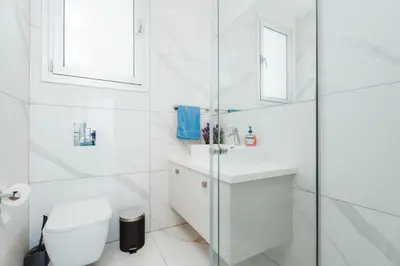 a white bathroom with a toilet and a sink at Seaside Luxury Villa with Heated Pool in Paralimni