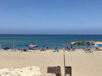 a beach with a bunch of chairs and umbrellas at Seaside Luxury Villa with Heated Pool in Paralimni