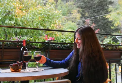 a woman sitting at a table with a glass of wine at Sophias Cottage in Askas