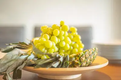 a bowl of green grapes on a wooden table at Protaras Art House Seviews in Protaras