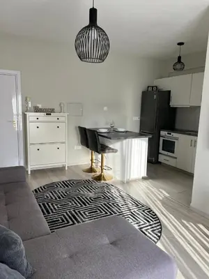 a living room with a table and a kitchen at Cozy Apartment by the sea in Limassol