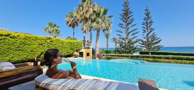 a woman talking on a cell phone next to a swimming pool at Villa del Mar Heated pool in Mazotos