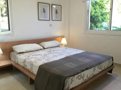 a bedroom with a large bed with two windows at Katikies Grand in Pissouri