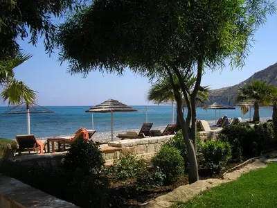 a beach with chairs and umbrellas and the ocean at Katikies Grand in Pissouri