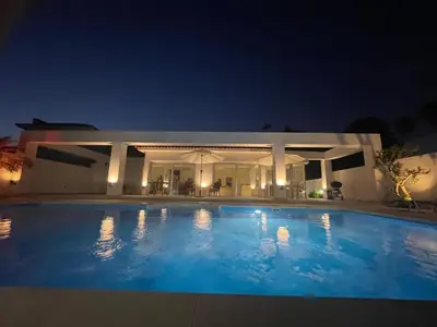 a large swimming pool in front of a house at night at Katikies Grand in Pissouri