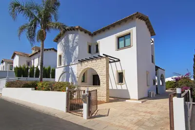 a large white house with a palm tree at Villa Greko in Protaras