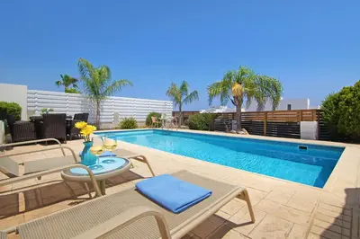a swimming pool with a table and chairs next to a pool at Villa Greko in Protaras