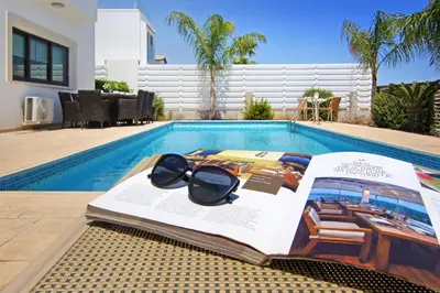 a book and sunglasses sitting next to a swimming pool at Villa Greko in Protaras