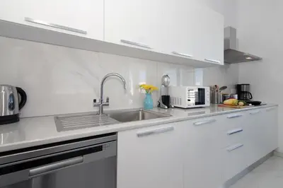 a white kitchen with a sink and a microwave at Villa Theresa in Protaras