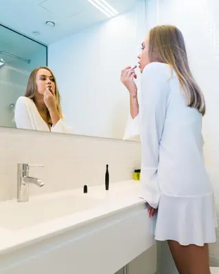 a woman brushing her teeth in front of a bathroom mirror at City Centre Studio Apartments Nicosia in Nicosia