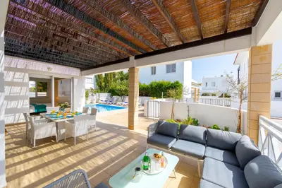 a patio with a blue couch and a table at Protaras Sapphire Seaside Villa in Protaras