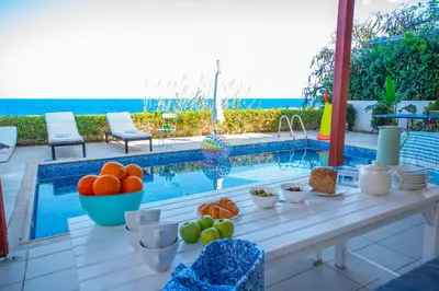 a table with fruit on it next to a swimming pool at Protaras Artisan Seafront Villa in Protaras